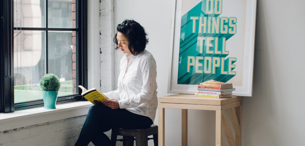 Women sitting next to sign that says 'Do Things. Tell People' to show personal branding